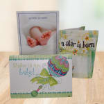 Three baby-themed greeting cards displayed on a table