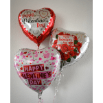 Three heart-shaped Valentine's Day balloons against a wall