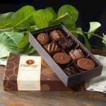 Box of assorted chocolates with green leaves behind it