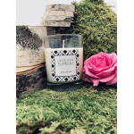 Pink rose beside a labeled glass candle on moss and wood
