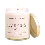 A lit jar candle with a gold lid and "congrats!" label