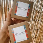 Two small cardboard boxes labeled Hibiscus Palm held in a hand