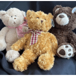 Three plush teddy bears with ribbon bows sitting together