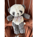 Plush panda bear with a plaid bow sitting on a wooden shelf