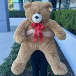 Large brown teddy bear with a red ribbon bow
