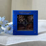 Blue chocolate box with four candies and pale blue flowers beside it