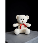 White teddy bear with a red ribbon sitting on a gray surface