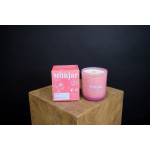 Pink candle in a glass jar beside its box on a wooden pedestal