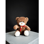 Brown teddy bear with a red ribbon sitting on a gray surface