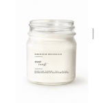 White soy candle in a clear glass jar with a printed label
