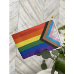 Rainbow pride flag beside a floral arrangement