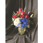 Red rose and purple iris arrangement with white hydrangea and blue bow in a glass vase