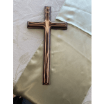 A bronze-colored cross resting on pale satin fabric.