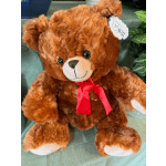 Brown teddy bear with a red ribbon sitting on a green surface