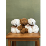Three plush teddy bears sit on a wooden table.