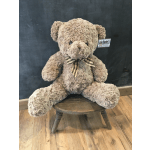 Large plush teddy bear with a plaid bow sitting on a small stool