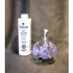 Purple floral candle in a glass dome beside a bottle of lamp oil