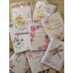 Assorted floral greeting cards in clear sleeves on a wooden surface