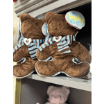 Two teddy bears with baby tags and striped bows on a shelf