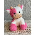 Pink and white plush cow toy sitting on a textured surface