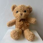 Teddy bear plush with a ribbon bow sitting on a surface