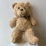 Teddy bear plush sitting on a small white container