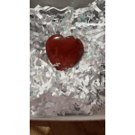 Red polished heart-shaped stone nestled in white crinkle paper filling