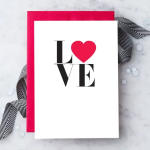 White greeting card with the word LOVE and a red heart on a red envelope