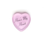 Pink heart-shaped candy with the words 'Here's My Heart' on a white background.