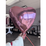 Pink heart-shaped foil balloon held indoors