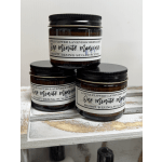 Three amber jars of lavender bergamot sugar scrub stacked on a wooden surface.