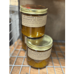 Two amber jar candles with gold lids stacked on a wire rack