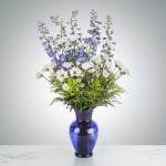 White daisies and blue delphinium in a cobalt glass vase