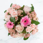 Pink roses and gerbera daisies arranged in a round bouquet