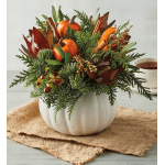 Autumn arrangement in a white pumpkin vase with orange pumpkins and greenery