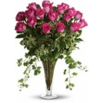 Pink rose bouquet in a tall vase with trailing greenery