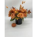 Orange floral arrangement in a black vase with a small pumpkin accent