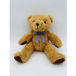 A plush teddy bear with a plaid bow sits on a plain background.