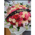 Large bouquet of pink, red, and cream roses with a birthday ribbon