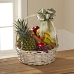 Fruit basket with pineapple, bananas, grapes, and other fruit in a white wicker basket