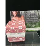 Decorative candle box with pink patterned packaging and a product display card behind it