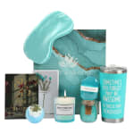 Teal self-care gift set with sleep mask, candle, tumbler, bath items, and cards
