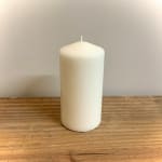 White pillar candle on a wooden surface