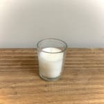 White candle in a clear glass holder on a wooden surface