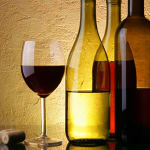 Wine glass beside several wine bottles