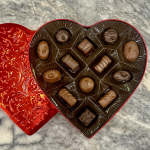 Heart-shaped box of assorted chocolates with a red lid
