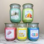 Five scented candles in glass jars with colorful labels