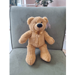 Plush teddy bear with a ribbon sitting on a chair