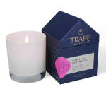Lit white candle beside a navy fragrance box