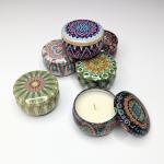 Decorative tin candles with patterned lids, one open to show wax